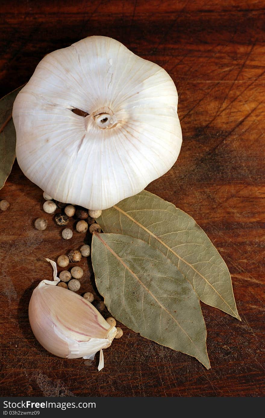 Garlic bulb and clove with spices on wooden cutting board (vertical image). Garlic bulb and clove with spices on wooden cutting board (vertical image)