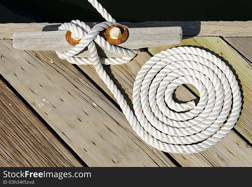 This is a photograph of a coiled rope tying a boat to a dock. This is a photograph of a coiled rope tying a boat to a dock.