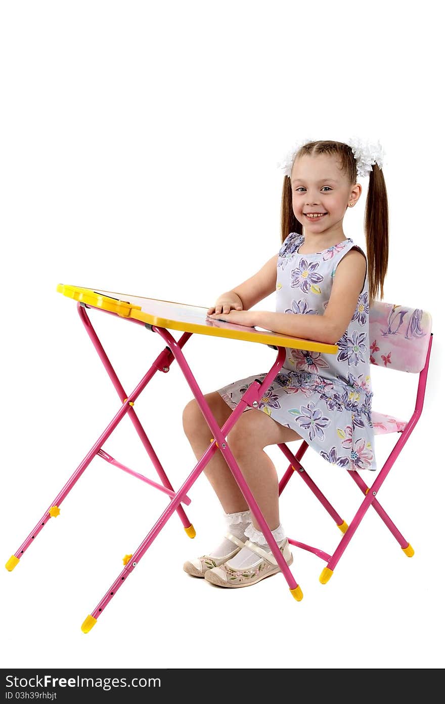 The little girl sits at a children's folding table