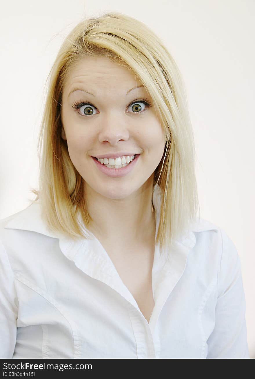 Wide eyed young blond woman in white shirt with surprised look. White background. Wide eyed young blond woman in white shirt with surprised look. White background