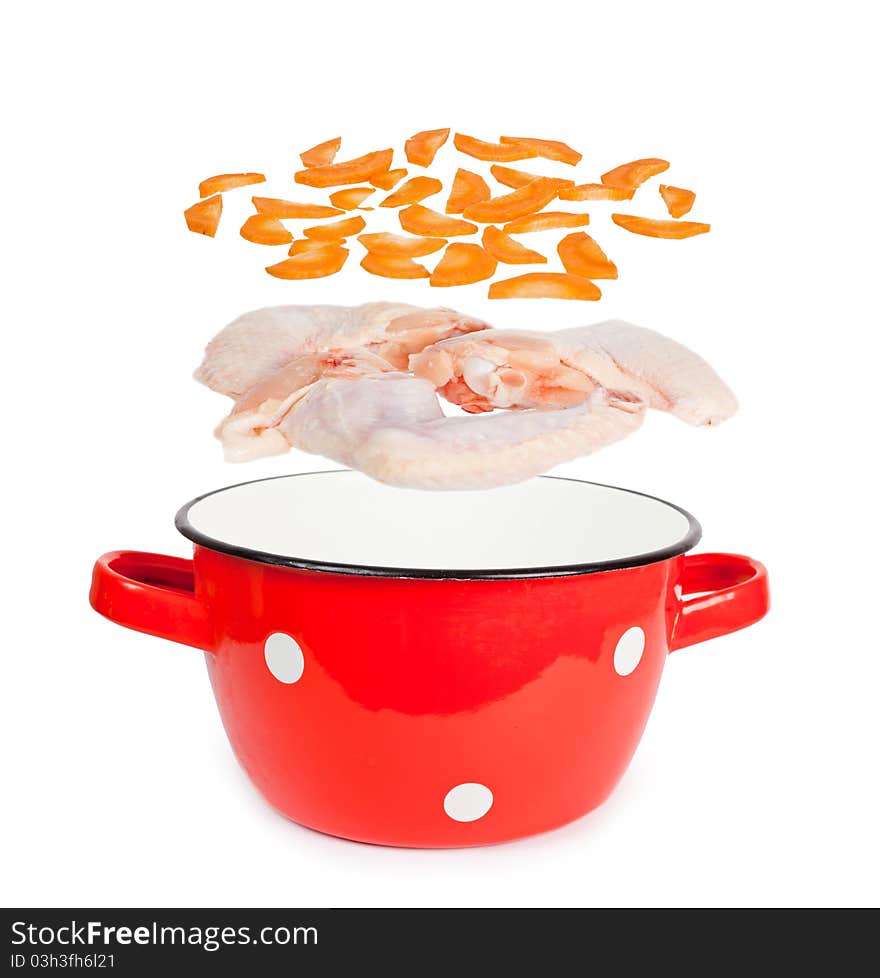 Red pot with white spots vintage with layers of chicken wings and carrots for soup preparation