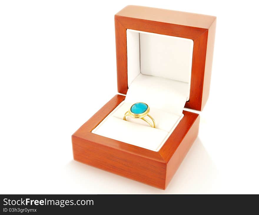 Blue gemstone on gold ring in a wooden box, isolated towards white. Blue gemstone on gold ring in a wooden box, isolated towards white