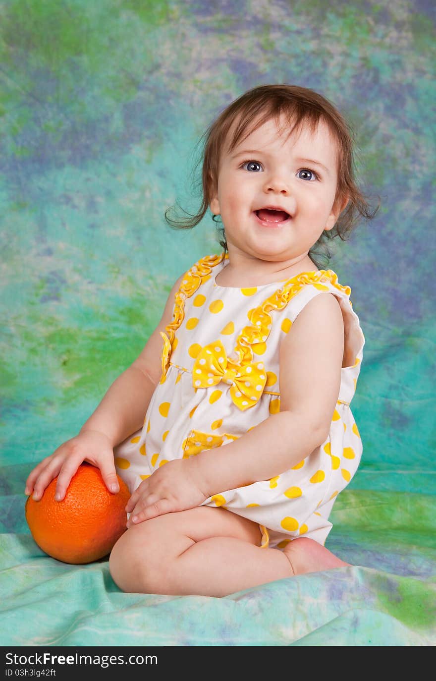 Little girl with the orange . she is sitting on the floor in studio