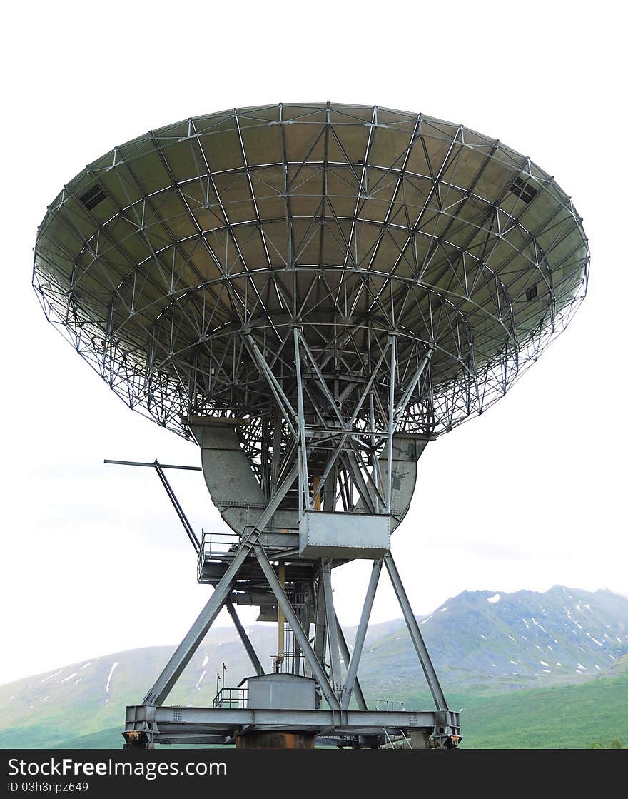 Large radio telescope is situated under green mountain. The sky is overcast. Large radio telescope is situated under green mountain. The sky is overcast.