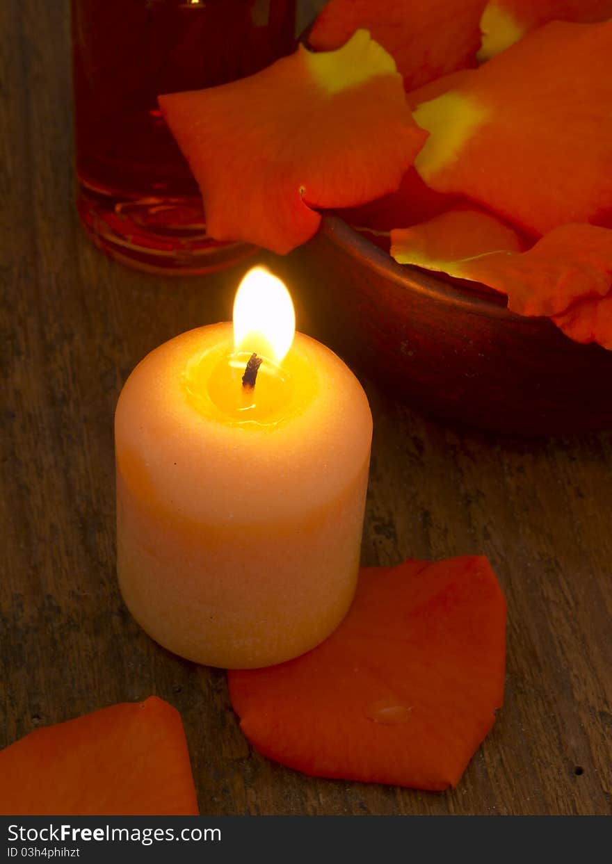 With burning candle and orange rose's petals. With burning candle and orange rose's petals