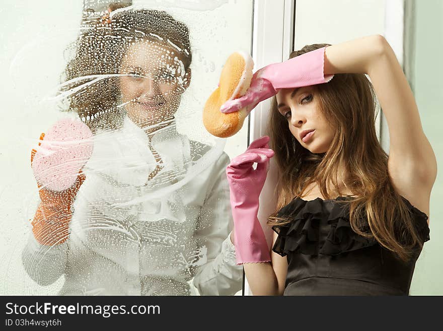 Attractive glamour girls washing the window with mop