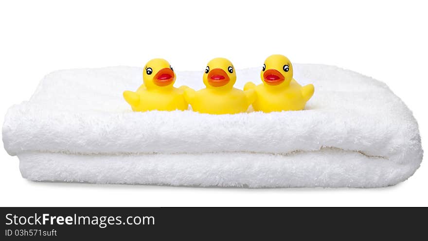 Three yellow rubber ducks in a row on a white fluffy towel isolated against a white background