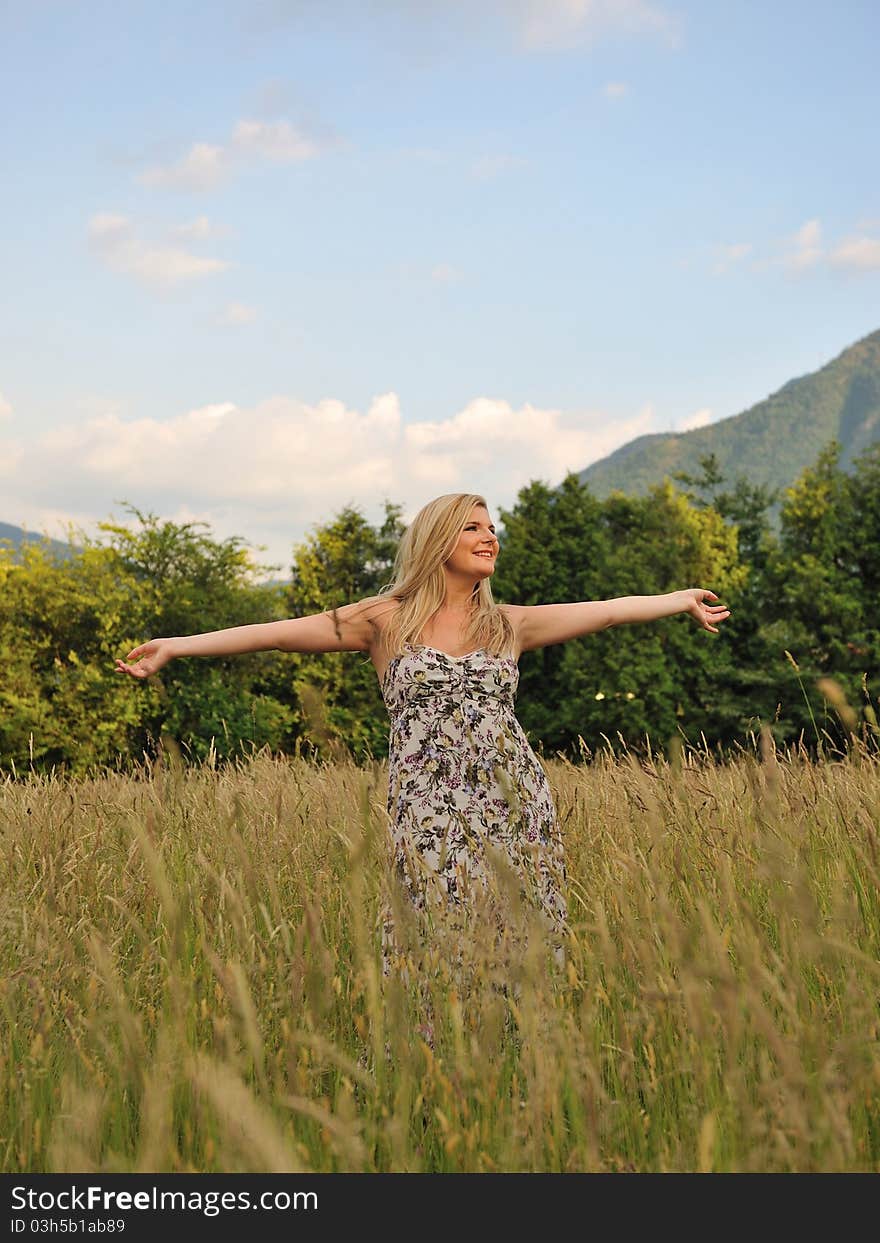 Pretty summer woman on yellow wheat field