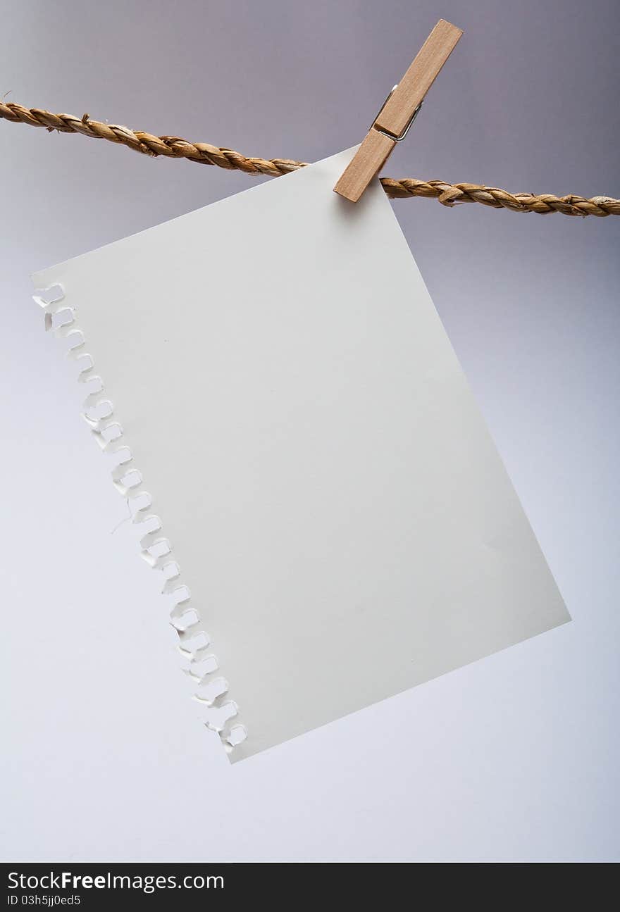 Close up of note pad and clothespins attached to a rope on white background. Close up of note pad and clothespins attached to a rope on white background