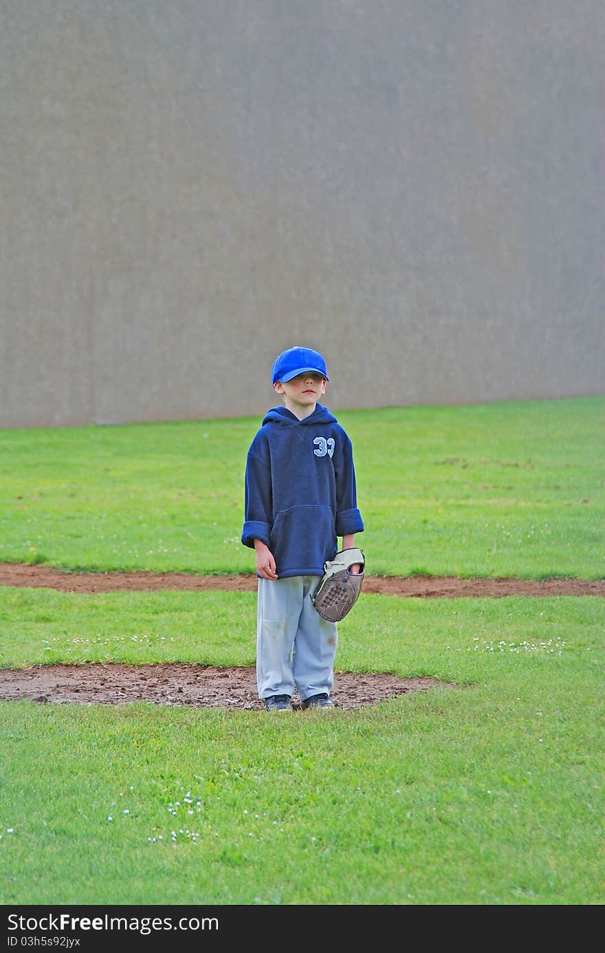 A young T-Ball player standing on the pitchers mound waiting for a player from the oppisite team to finally hit the ball after 10 tries. A young T-Ball player standing on the pitchers mound waiting for a player from the oppisite team to finally hit the ball after 10 tries.