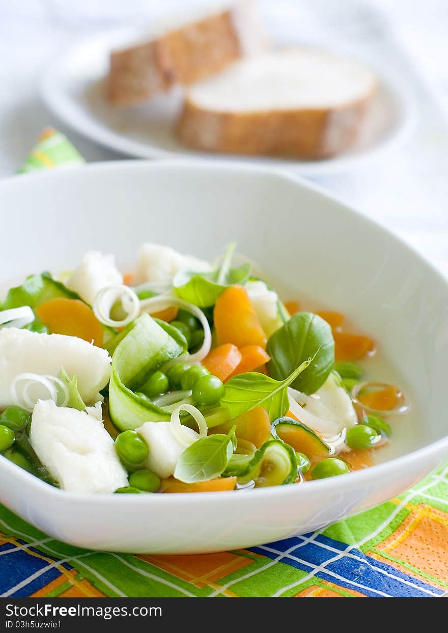 Vegetable soup with fish in a white plate