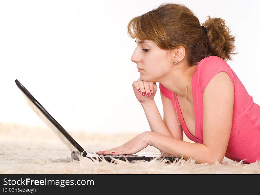 Beautiful girl lying on carpet with a laptop. Beautiful girl lying on carpet with a laptop