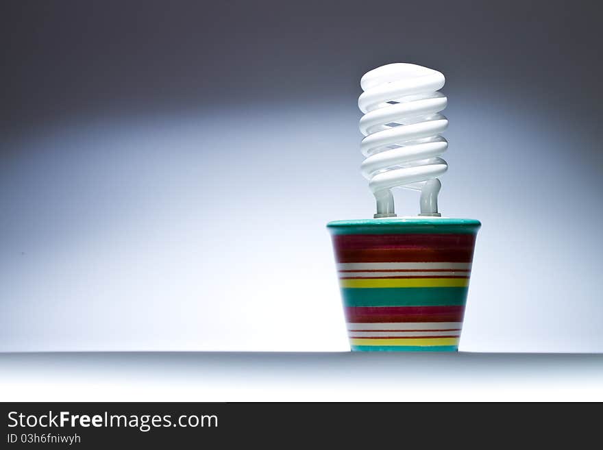 Energy saving lamp growing in a flower pot. Horizontal image. Energy saving lamp growing in a flower pot. Horizontal image