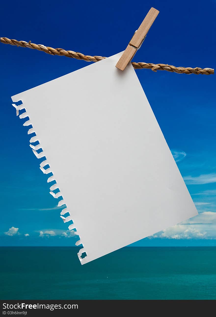 Close up of note pad and clothespins attached to a rope on blue sky background. Close up of note pad and clothespins attached to a rope on blue sky background