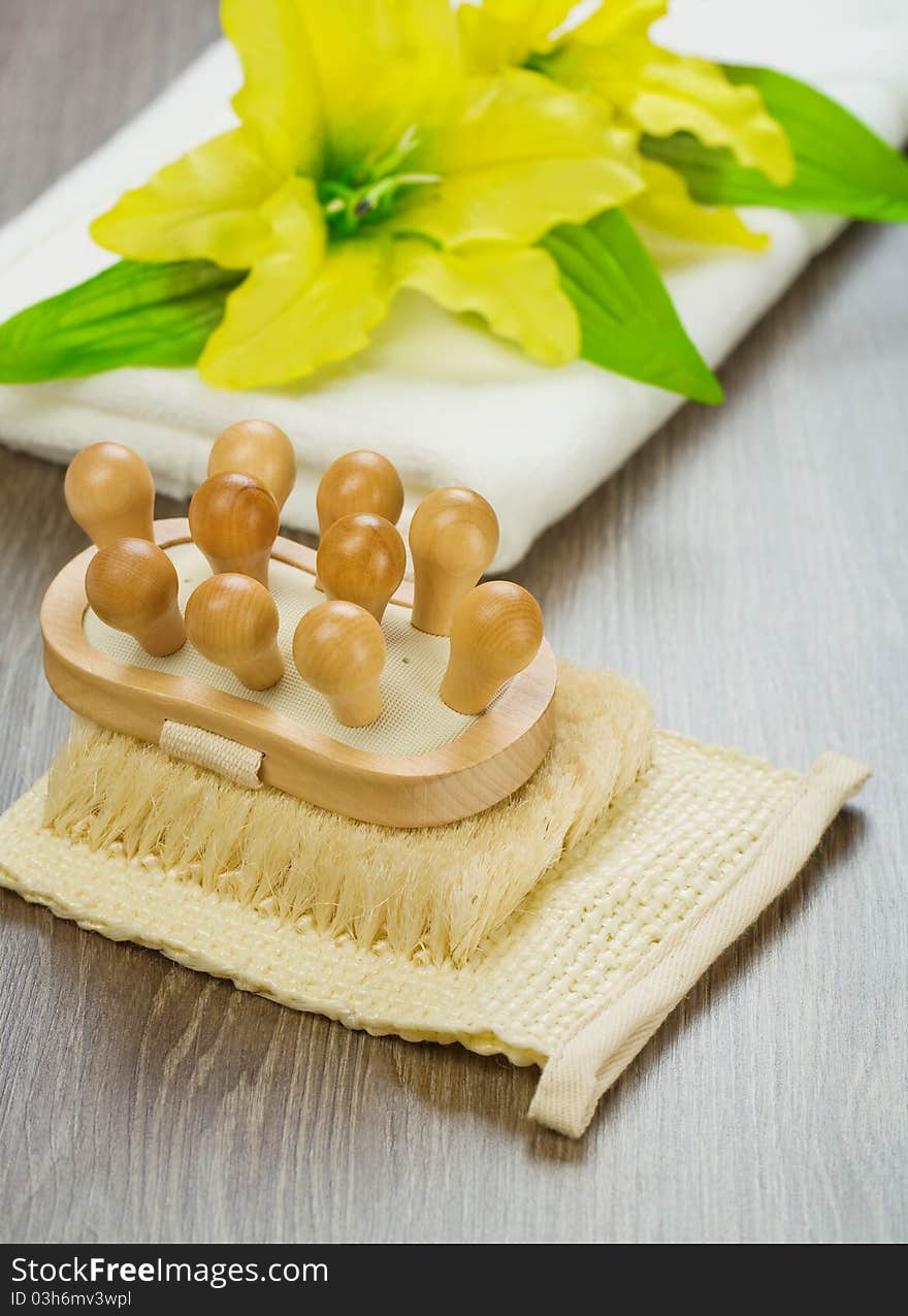 Studio shot view on the batching accessories wooden massager on the natural bast yellow flover with leaves on white cootton towels and all its on wooden boards. Studio shot view on the batching accessories wooden massager on the natural bast yellow flover with leaves on white cootton towels and all its on wooden boards