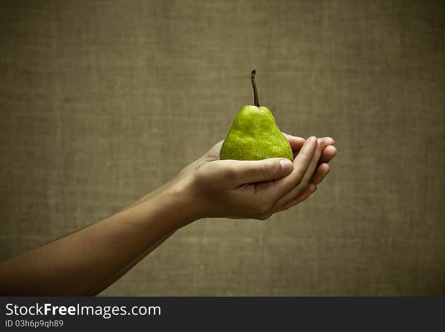 Green pear in female hands. Natural rural style image