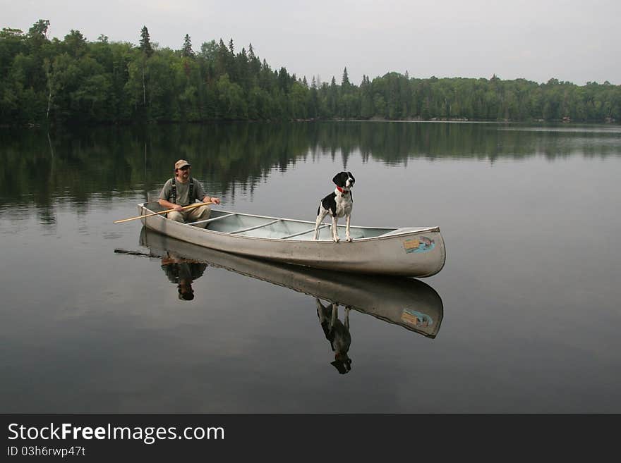 Canoeist with a Springer Spaniel dog in the bow of a canoe. Canoeist with a Springer Spaniel dog in the bow of a canoe