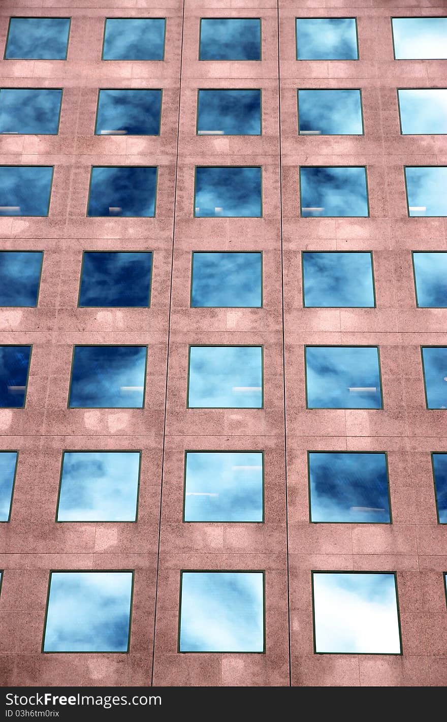 An office building with its windows reflecting the blue sky and white clouds. An office building with its windows reflecting the blue sky and white clouds