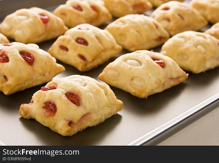 Strawberry strudel bites in rolls on a cookie sheet. Strawberry strudel bites in rolls on a cookie sheet.