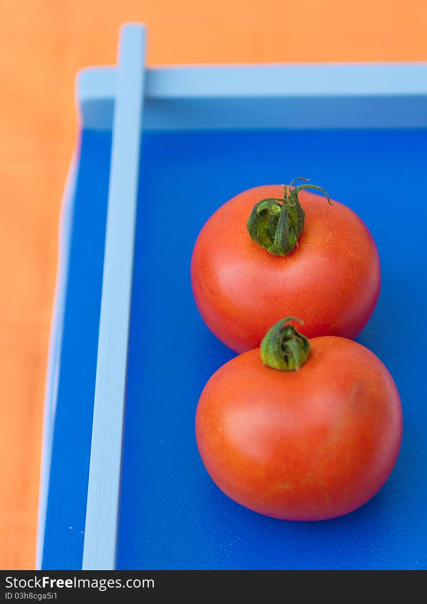 Two tomatoes on a blue background