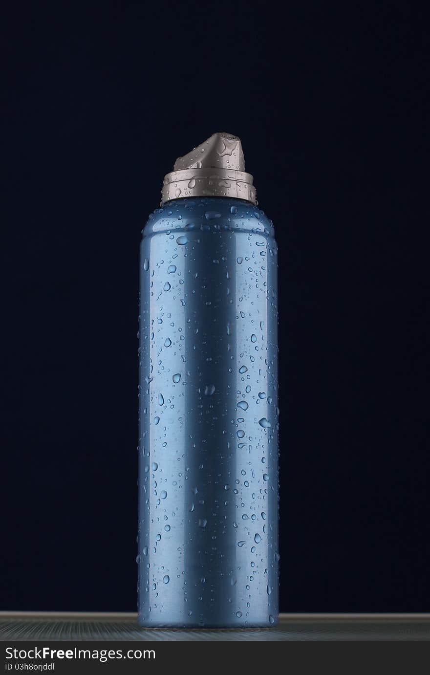 The aerosol shaving foam on dark blue background with drops of water