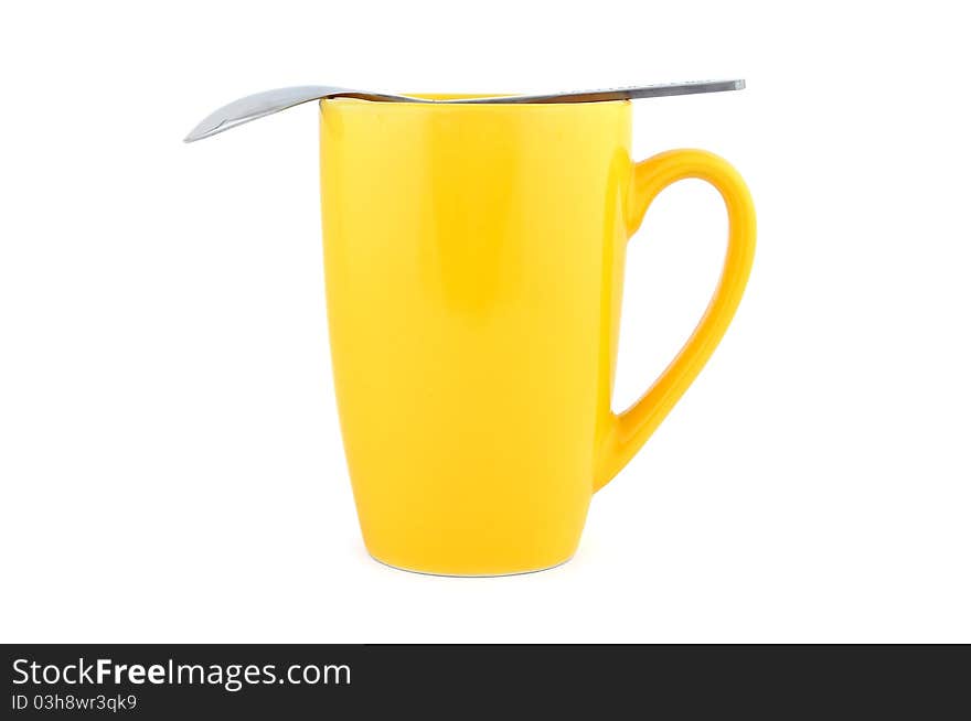 Empty yellow cup and spoon on a white background