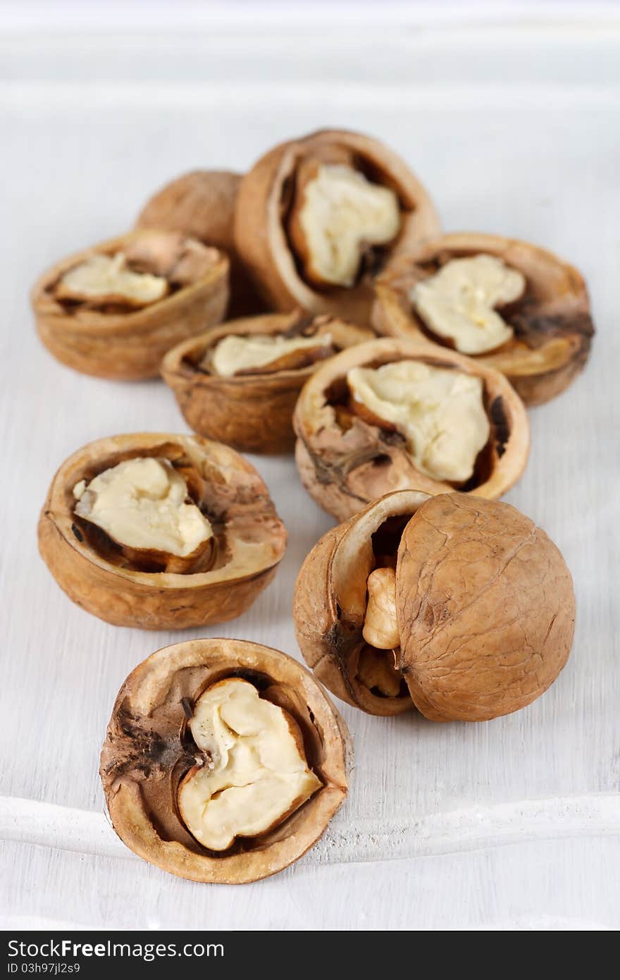 Scattering choped garden walnuts on a white wooden board. Scattering choped garden walnuts on a white wooden board.