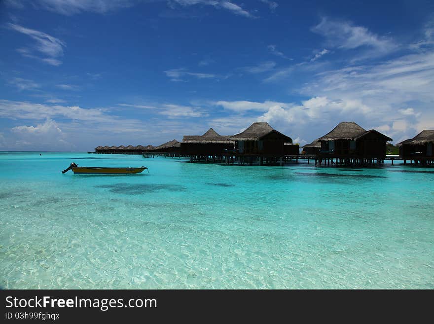 Turquoise seascape with blue sky, cloudscape and Maldives shoreline in background,water villas. Turquoise seascape with blue sky, cloudscape and Maldives shoreline in background,water villas