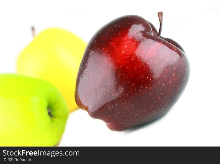 Three different color apples, focus on red one