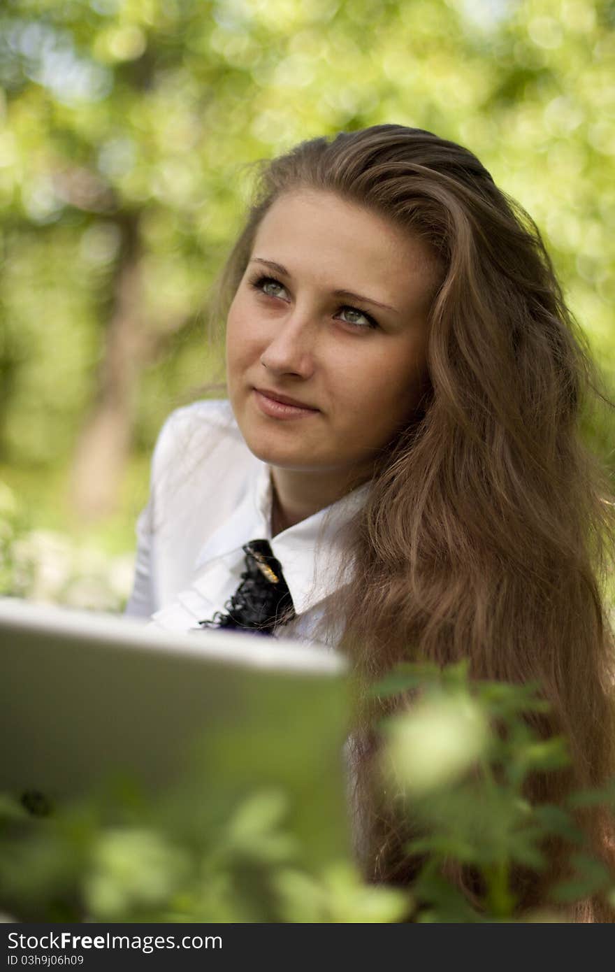 Girl with laptop lying on the lawn in thought