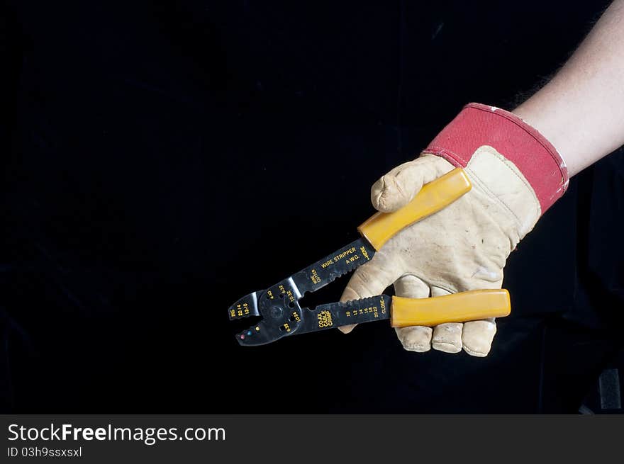 Hand with work glove and wire stripper tool