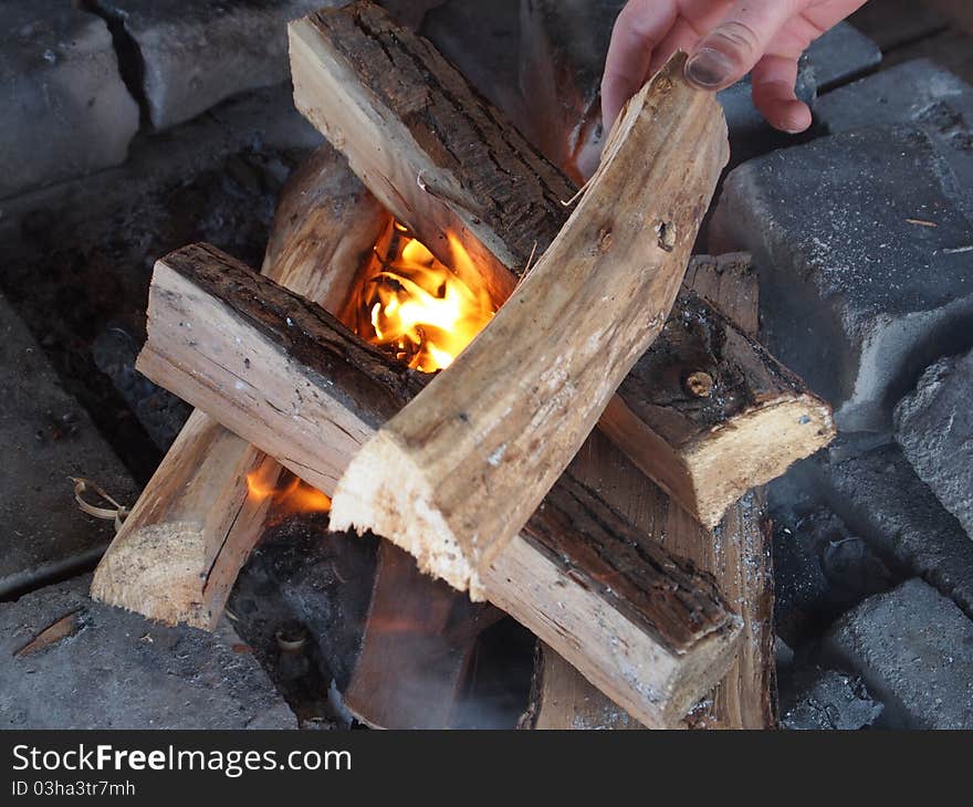 Hand putting wood on a Campfire