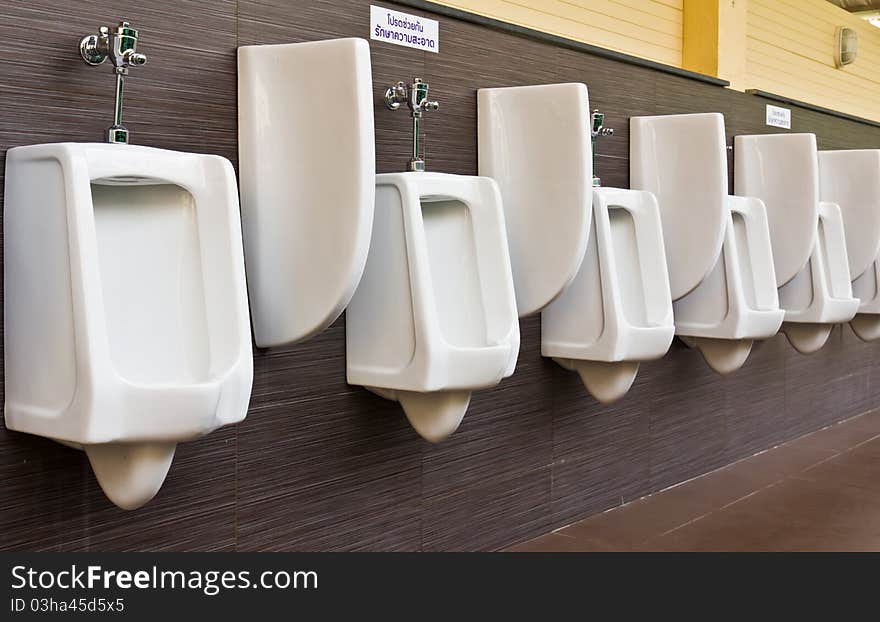 Row of white porcelain urinals in public toilets