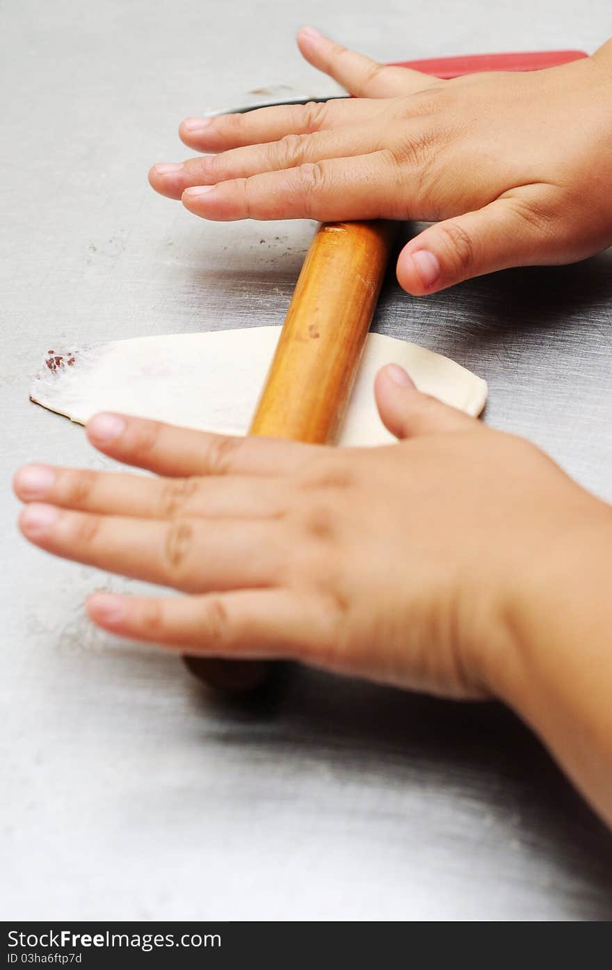 Hand rolled the dough using wood roller on the silver kitchen table with both hands