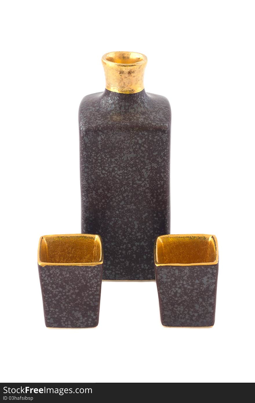 Brown and gold square ceramic sake bottle with two cups isolated on white.