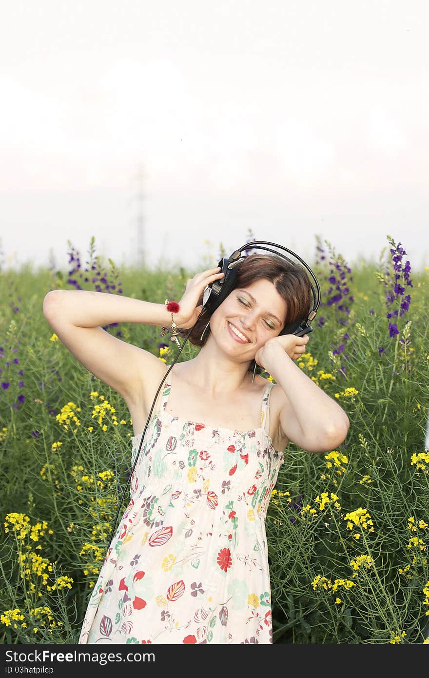 Portrait of girl who listening music in ear-phones on a field of flowers. Portrait of girl who listening music in ear-phones on a field of flowers