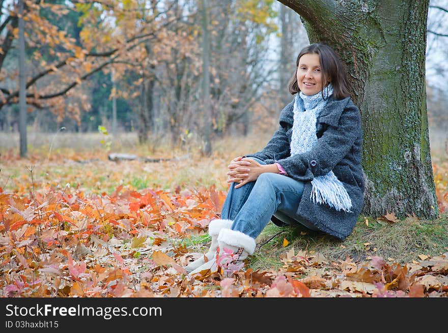 Cute happy young woman sitting in the autumn park. Cute happy young woman sitting in the autumn park.