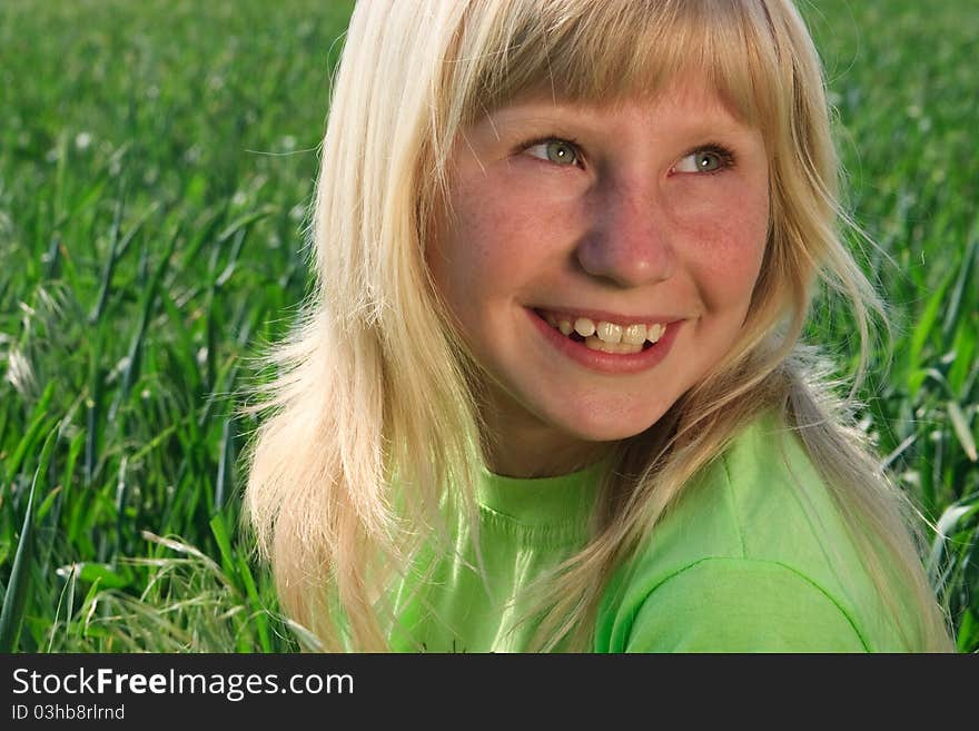 Happy young girl with smile on the  background of the green field