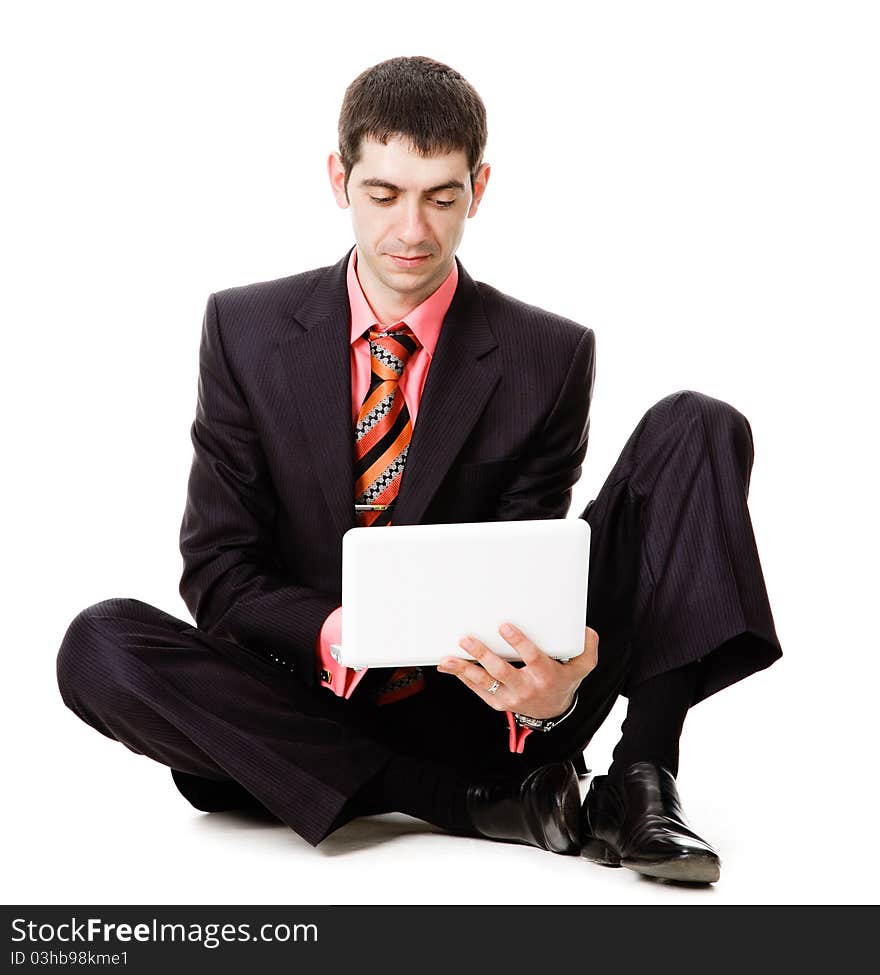 A young man sits on the floor and watches at a laptop, isolated on a white background. A young man sits on the floor and watches at a laptop, isolated on a white background.