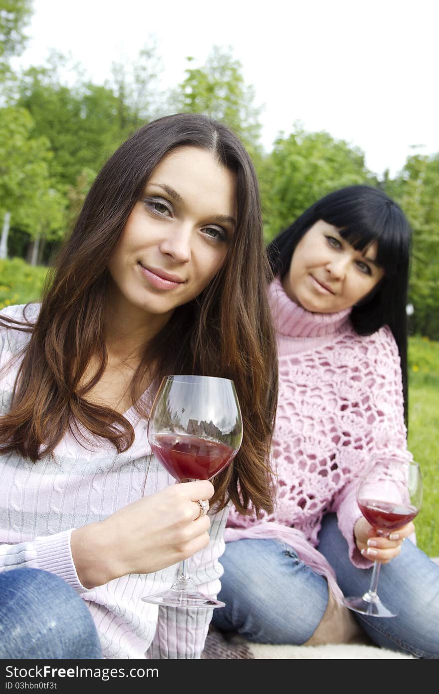 Mother and daughter drinking wine outdoors