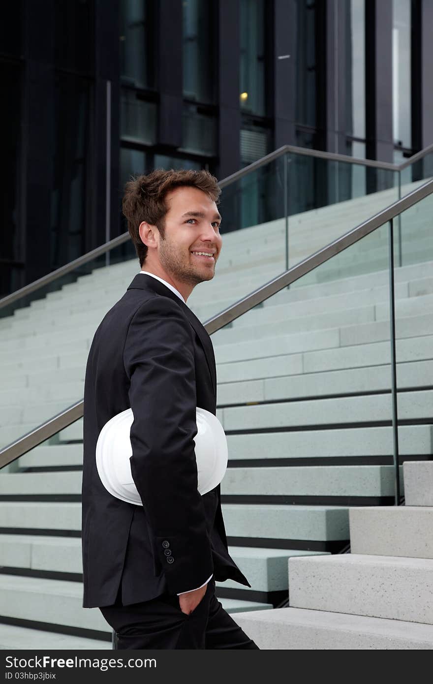 Business man standing at stairs with helmet