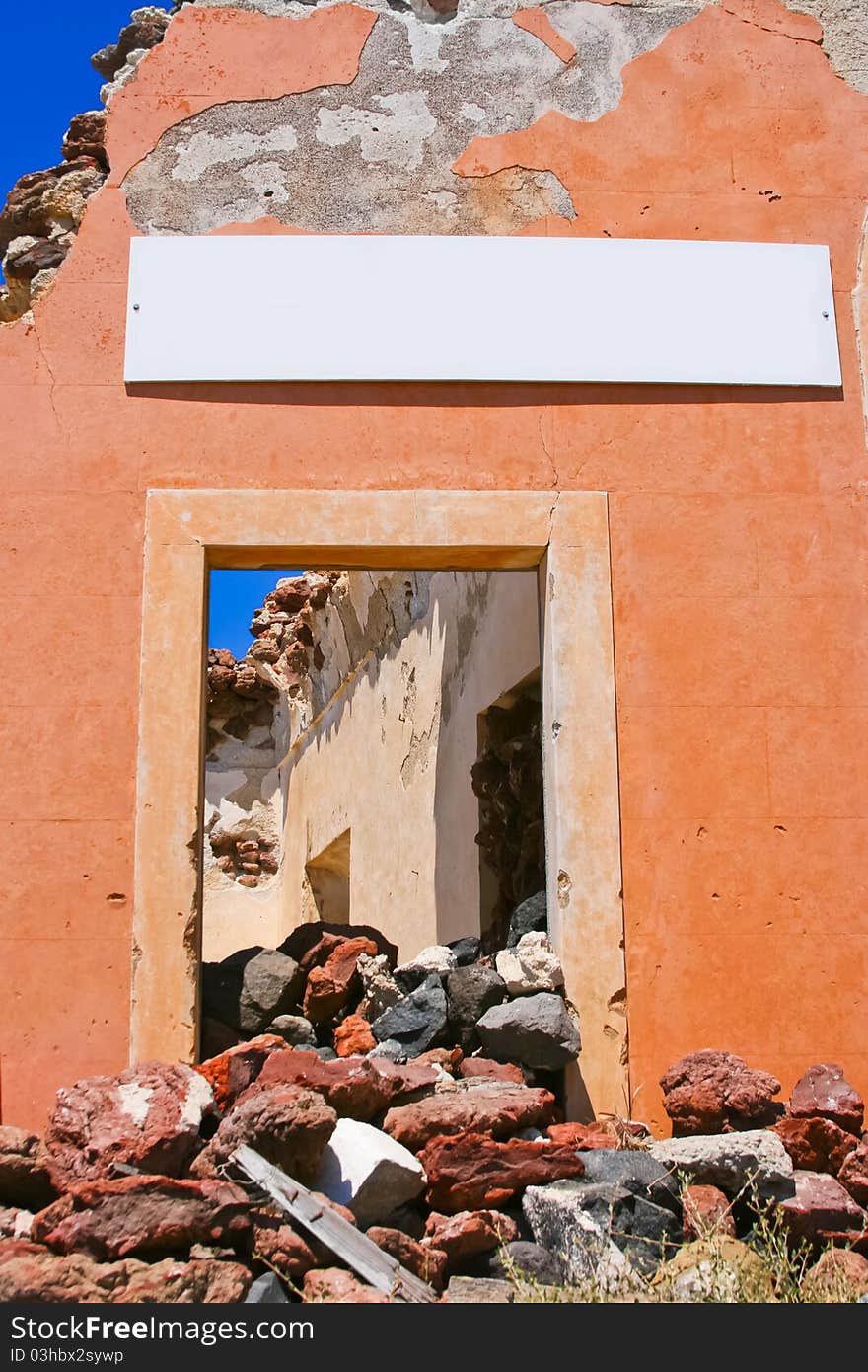 Damaged entrance with empty billboard in Santorini