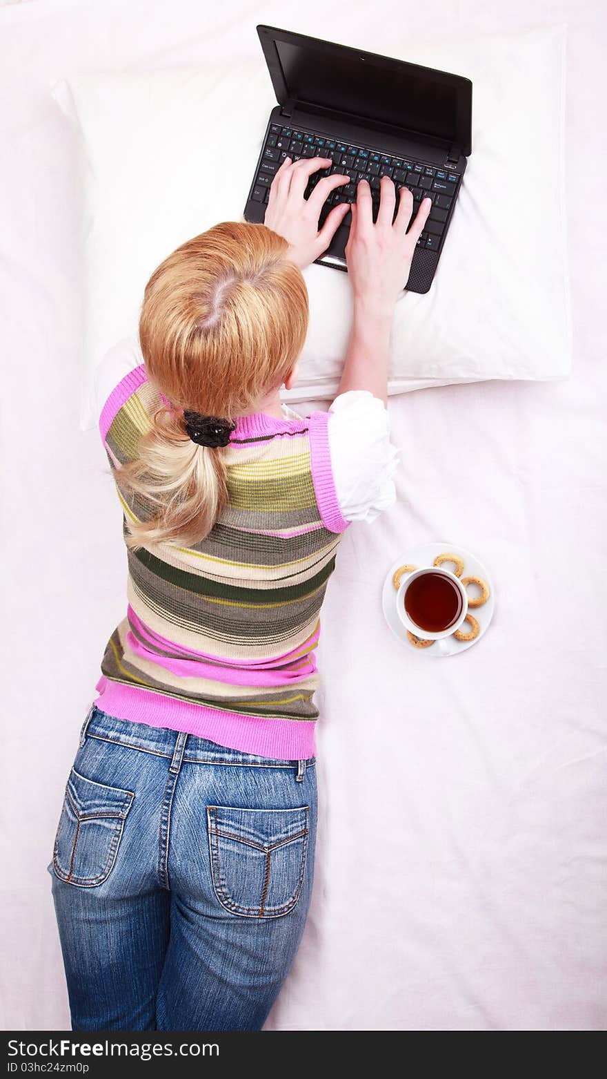 A young girl working on computer in bed. A young girl working on computer in bed