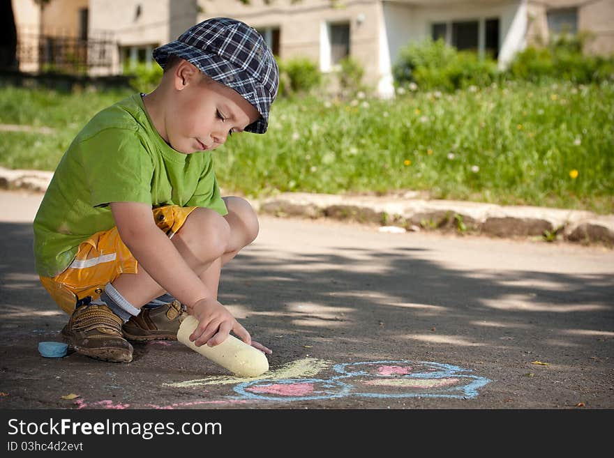 Boy drawing with chalk on asphalt