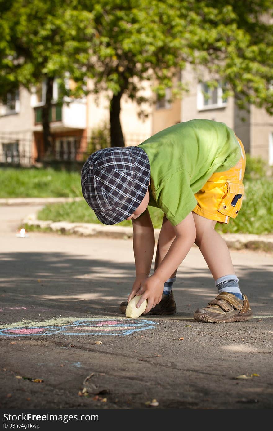 Boy drawing with chalk on asphalt