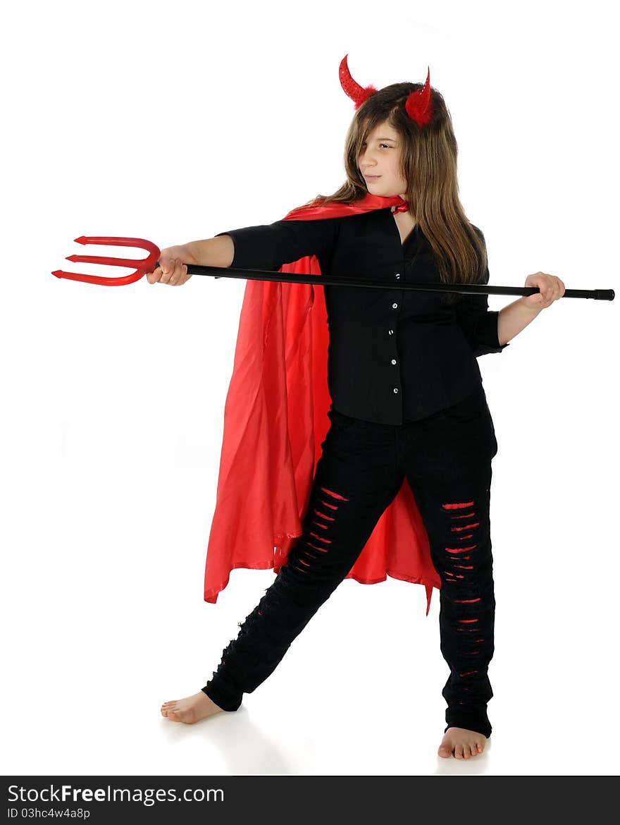 A pretty preteen dressed as a she-devil taking aim with her pitchfork. Isolated on white.