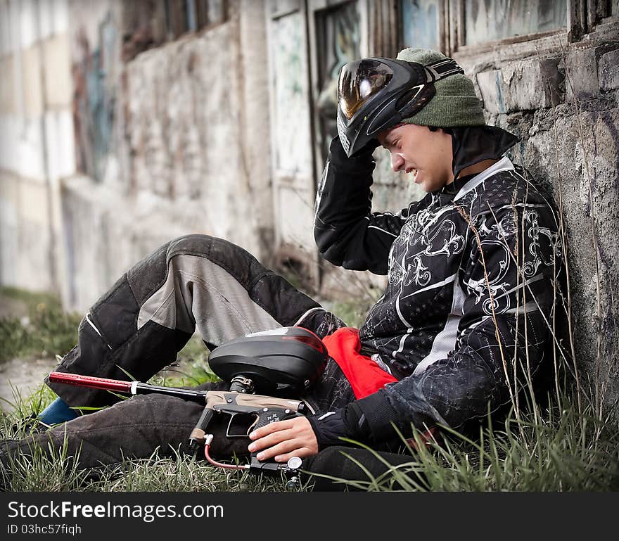 Paintball player relaxing with marker in grunge background