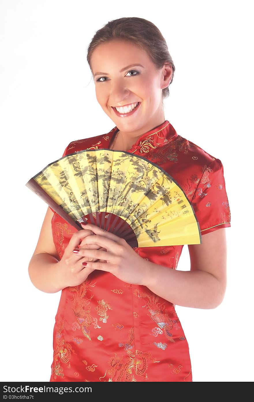 The beautiful young girl in a red Chinese dress with a yellow fan in hands. The beautiful young girl in a red Chinese dress with a yellow fan in hands