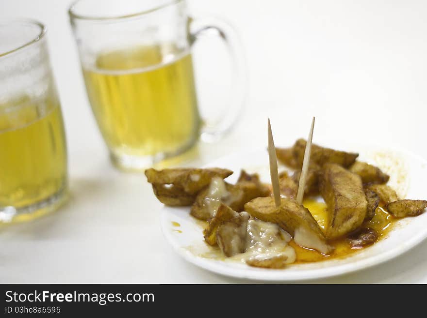 Patatas bravas and two beers on white background. Patatas bravas and two beers on white background