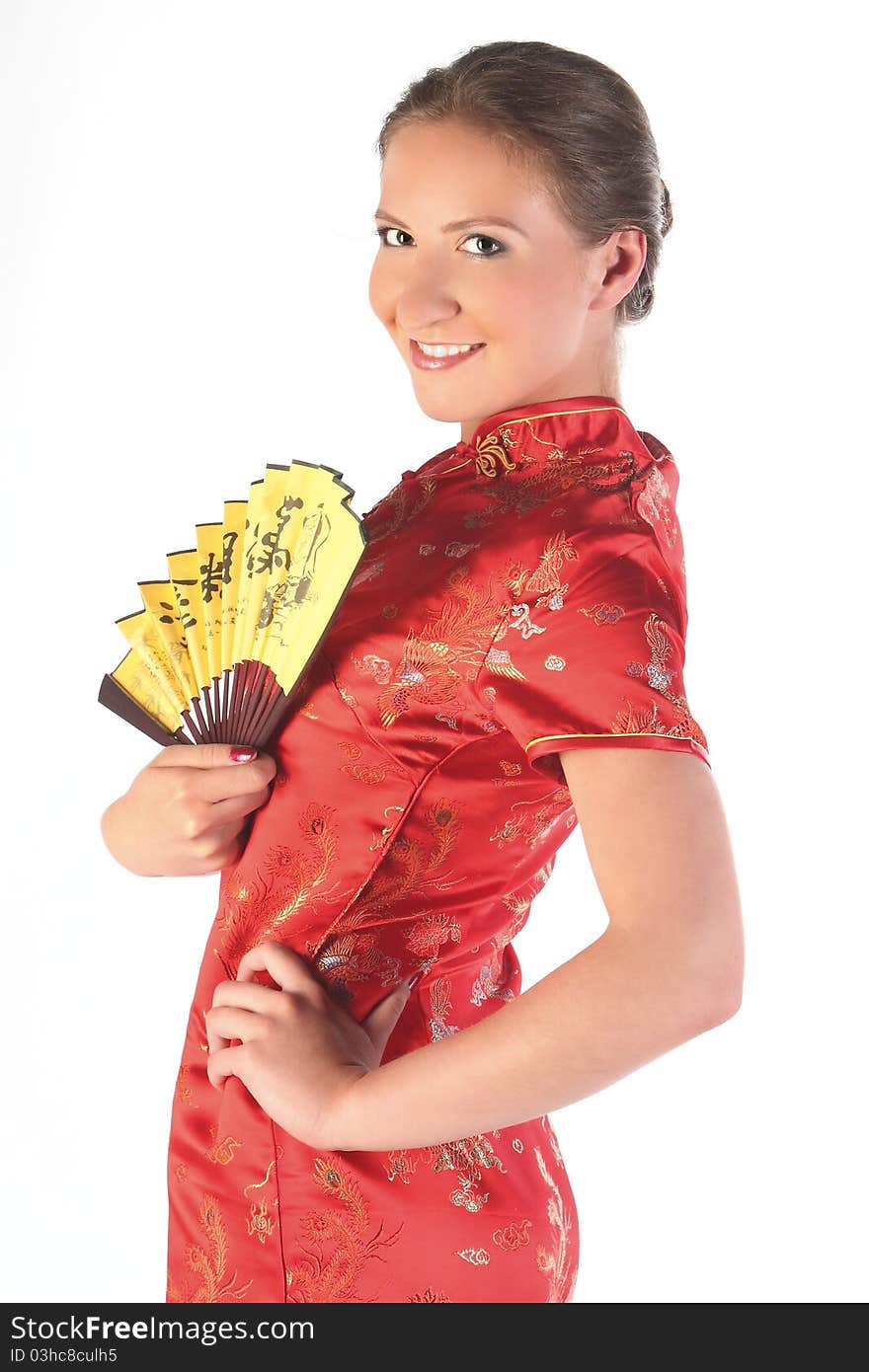 The beautiful young girl in a red Chinese dress with a yellow fan in hands. The beautiful young girl in a red Chinese dress with a yellow fan in hands